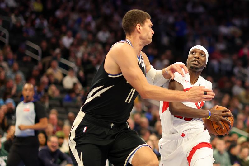 MILWAUKEE, WISCONSIN - NOVEMBER 12: Chris Boucher #25 of the Toronto Raptors drives to the basket against Brook Lopez #11 of the Milwaukee Bucks during the first half of a game in the NBA Emirates Cup at Fiserv Forum on November 12, 2024 in Milwaukee, Wisconsin. NOTE TO USER: User expressly acknowledges and agrees that, by downloading and or using this photograph, User is consenting to the terms and conditions of the Getty Images License Agreement. (Photo by Stacy Revere/Getty Images)