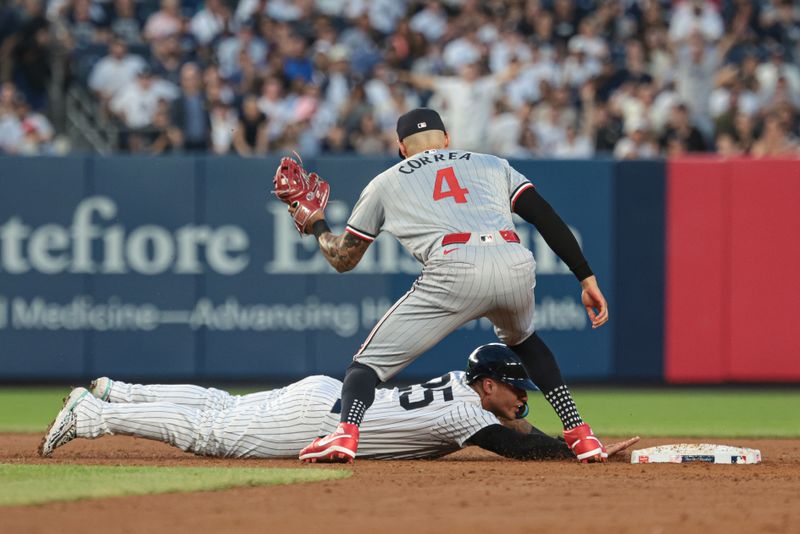 Jun 6, 2024; Bronx, New York, USA; New York Yankees second baseman Gleyber Torres (25) slides safely back to second base under a tag by Minnesota Twins shortstop Carlos Correa (4) during the third inning at Yankee Stadium. Mandatory Credit: Vincent Carchietta-USA TODAY Sports