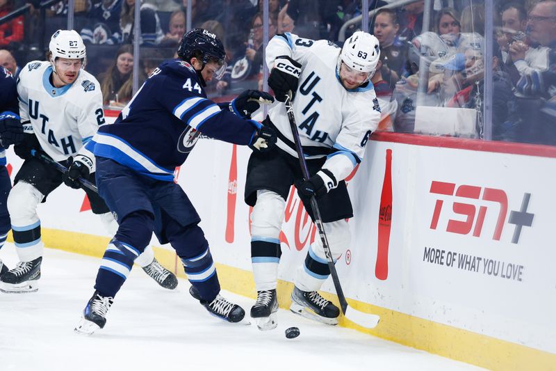 Nov 5, 2024; Winnipeg, Manitoba, CAN;  Winnipeg Jets defenseman Josh Morrissey (44) battles Utah Hockey Club forward Matias Marcelli (63) for the puck during the first period at Canada Life Centre. Mandatory Credit: Terrence Lee-Imagn Images