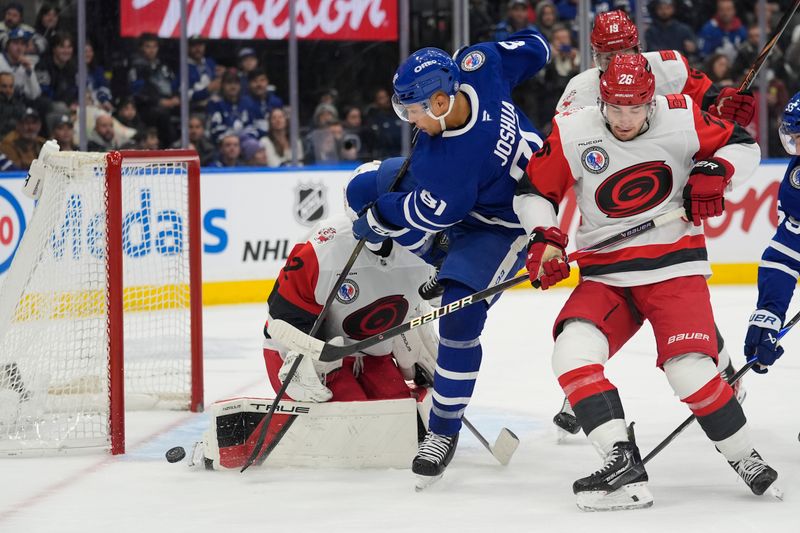 Nov 9, 2025; Toronto, Ontario, CAN; Toronto Maple Leafs forward Dakota Joshua (81) tries to tip a shot past Carolina Hurricanes goaltender Brandon Bussi (32) as  defenseman Sean Walker (26) helps defend during the first period at Scotiabank Arena. Mandatory Credit: John E. Sokolowski-Imagn Images