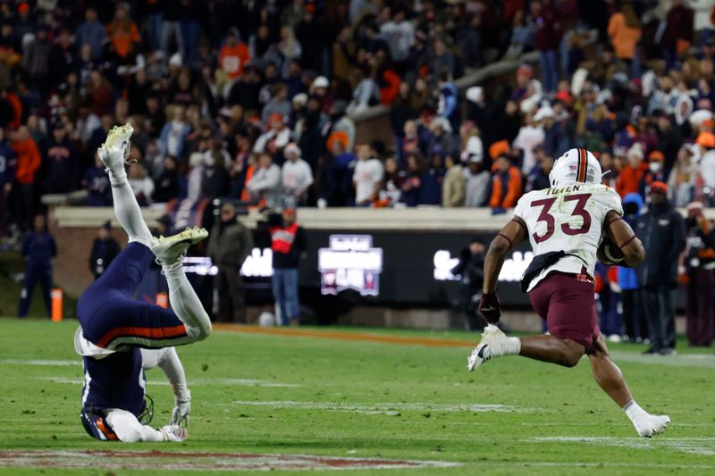 Nov 25, 2023; Charlottesville, Virginia, USA; Virginia Tech Hokies running back Bhayshul Tuten (33) carries the ball past Virginia Cavaliers cornerback Sam Westfall (13) during the third quarter at Scott Stadium. Mandatory Credit: Geoff Burke-USA TODAY Sports