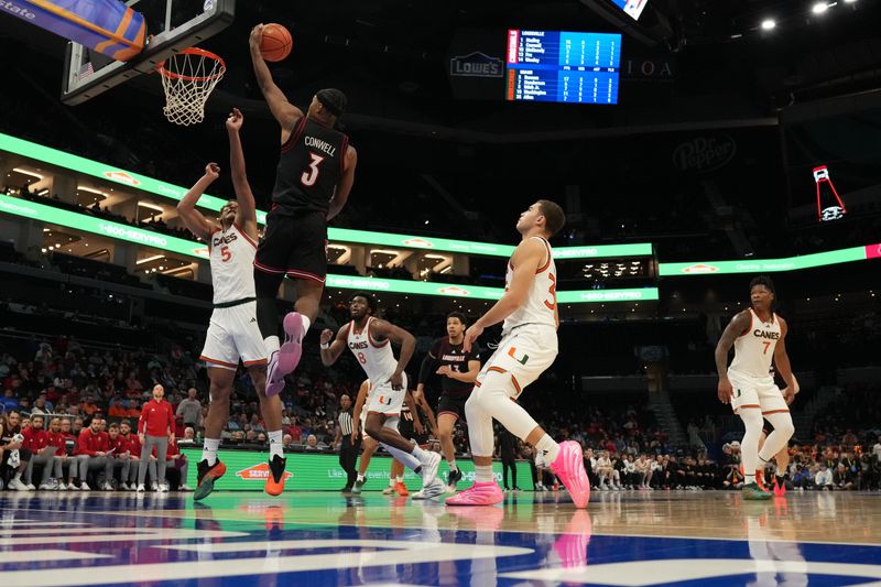 Mar 12, 2026; Charlotte, NC, USA; Louisville Cardinals guard Ryan Conwell (3) goes to the basket guarded by Miami (FL) Hurricanes forward Malik Reneau (5) during the second half at Spectrum Center. Mandatory Credit: Jim Dedmon-Imagn Images