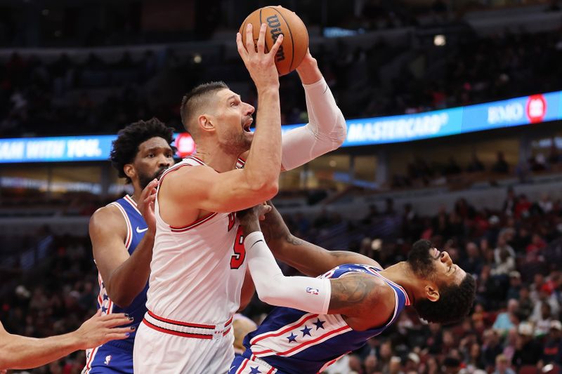 CHICAGO, ILLINOIS - DECEMBER 08: Nikola Vucevic #9 of the Chicago Bulls is called for a offensive foul against Paul George #8 of the Philadelphia 76ers during the second half at the United Center on December 08, 2024 in Chicago, Illinois. NOTE TO USER: User expressly acknowledges and agrees that, by downloading and or using this photograph, User is consenting to the terms and conditions of the Getty Images License Agreement.  (Photo by Michael Reaves/Getty Images)