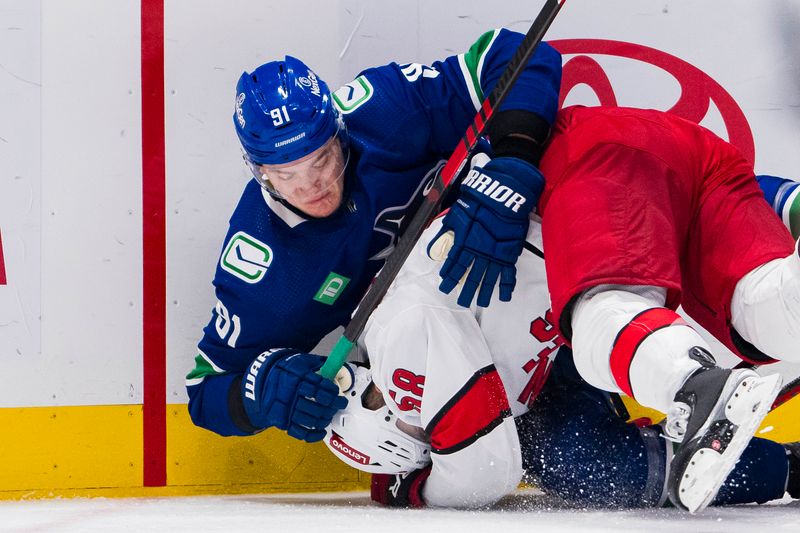 Dec 9, 2023; Vancouver, British Columbia, CAN; Vancouver Canucks defenseman Nikita Zadorov (91) tackles Carolina Hurricanes forward Michael Bunting (58) in the second period at Rogers Arena. Mandatory Credit: Bob Frid-USA TODAY Sports