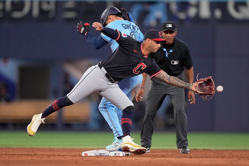 May 4, 2025; Toronto, Ontario, CAN; Cleveland Guardians shortstop Brayan Rocchio (4) makes a catch at second base as Toronto Blue Jays second baseman Andres Gimenez (0) reaches second base on an error during the ninth inning at Rogers Centre. Mandatory Credit: John E. Sokolowski-Imagn Images