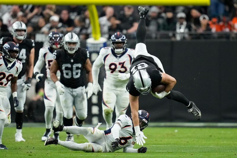 Las Vegas Raiders tight end Austin Hooper, right, is upended by a hit from Denver Broncos safety P.J. Locke (6) during the first half of an NFL football game, Sunday, Jan. 7, 2024 in Las Vegas. (AP Photo/John Locher)