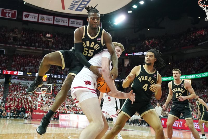 Feb 4, 2024; Madison, Wisconsin, USA; Wisconsin Badgers forward Steven Crowl (22) is fouled by Purdue Boilermakers guard Lance Jones (55) as he rebounds the ball and Purdue Boilermakers forward Trey Kaufman-Renn (4) looks on during the second half at the Kohl Center. Mandatory Credit: Kayla Wolf-USA TODAY Sports