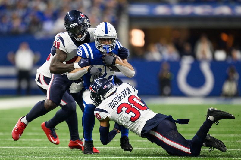 Houston Texans safety DeAndre Houston-Carson (30) and Houston Texans linebacker Christian Harris (48) bring down Indianapolis Colts running back Jonathan Taylor (28) during an NFL football game, Saturday, Jan. 6, 2024, in Indianapolis. (AP Photo/Zach Bolinger)