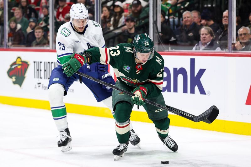 Dec 3, 2024; Saint Paul, Minnesota, USA; Minnesota Wild center Marco Rossi (23) and Vancouver Canucks defenseman Vincent Desharnais (73) compete for the puck during the second period at Xcel Energy Center. Mandatory Credit: Matt Krohn-Imagn Images