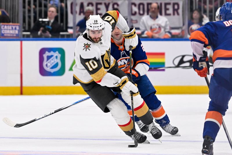 Jan 23, 2024; Elmont, New York, USA;  Vegas Golden Knights center Nicolas Roy (10) skates with the puck defended by New York Islanders defenseman Noah Dobson (8) during the third period at UBS Arena. Mandatory Credit: Dennis Schneidler-USA TODAY Sports