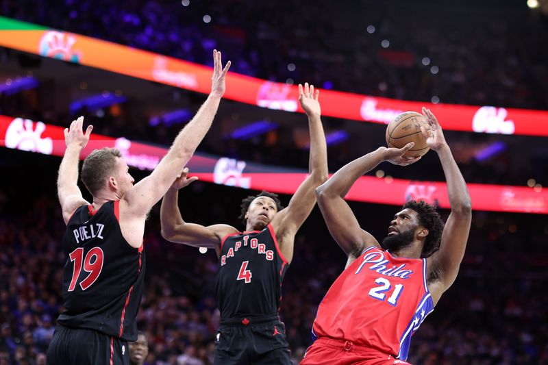 PHILADELPHIA, PENNSYLVANIA - DECEMBER 22: Joel Embiid #21 of the Philadelphia 76ers shoots over Jakob Poeltl #19 and Scottie Barnes #4 of the Toronto Raptors during the third quarter at the Wells Fargo Center on December 22, 2023 in Philadelphia, Pennsylvania. NOTE TO USER: User expressly acknowledges and agrees that, by downloading and or using this photograph, User is consenting to the terms and conditions of the Getty Images License Agreement. (Photo by Tim Nwachukwu/Getty Images)