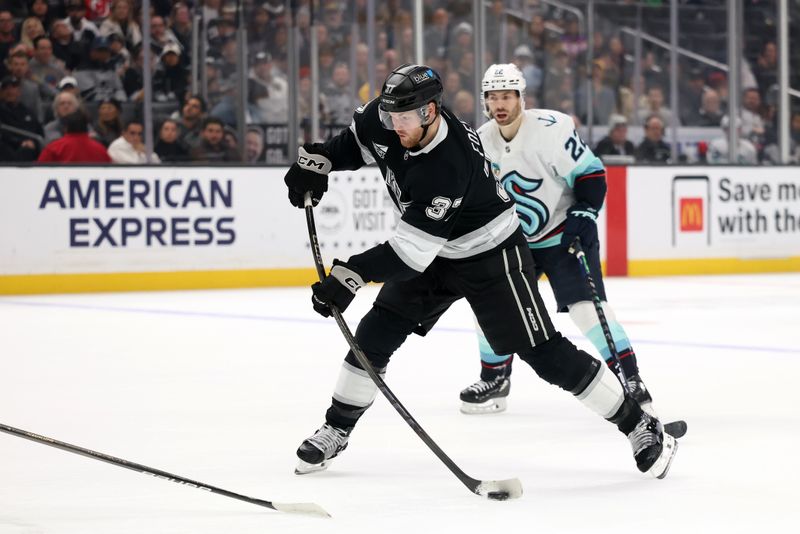 Nov 23, 2024; Los Angeles, California, USA;  Los Angeles Kings left wing Warren Foegele (37) shoots against Seattle Kraken right wing Oliver Bjorkstrand (22) during the second period at Crypto.com Arena. Mandatory Credit: Kiyoshi Mio-Imagn Images