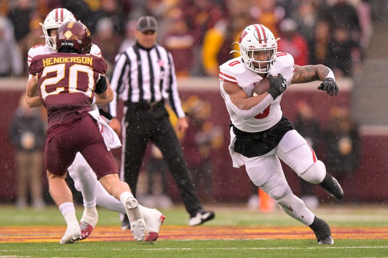 Nov 25, 2023; Minneapolis, Minnesota, USA;  Wisconsin Badgers running back Braelon Allen (0) runs with the ball as quarterback Tanner Mordecai (8) puts a block on Minnesota Golden Gophers defensive back Jack Henderson (20) at Huntington Bank Stadium. Mandatory Credit: Nick Wosika-USA TODAY Sports