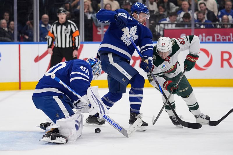 Jan 19, 2026; Toronto, Ontario, CAN; Toronto Maple Leafs goaltender Joseph Woll (60) makes a save and defenseman Simon Benoit (2) defends against Minnesota Wild forward Hunter Haight (37) during the second period at Scotiabank Arena. Mandatory Credit: John E. Sokolowski-Imagn Images
