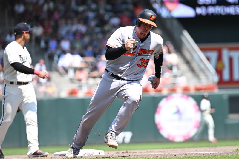 Jul 9, 2023; Minneapolis, Minnesota, USA; Baltimore Orioles catcher Adley Rutschman (35) scores on a RBI single by first baseman Ryan Mountcastle (not pictured) as Minnesota Twins third baseman Donovan Solano (39) looks on during the fifth inning at Target Field. Mandatory Credit: Jeffrey Becker-USA TODAY Sports