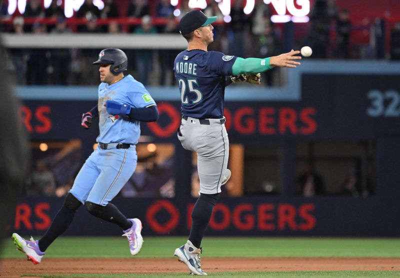 Apr 20, 2025; Toronto, Ontario, CAN; Seattle Mariners shortstop Ryan Moore (25) passes by Toronto Blue Jays center fielder George Springer (4) as he throws to first base to force out pinch hitter Will Wagner (not shown) in the seventh inning at Rogers Centre. Mandatory Credit: Dan Hamilton-Imagn Images
