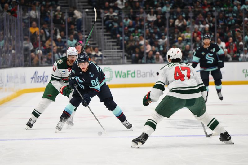 Mar 4, 2025; Seattle, Washington, USA; Seattle Kraken left wing Andre Burakovsky (95) advances the puck while defended by Minnesota Wild left wing Marcus Foligno (17) and Minnesota Wild defenseman Declan Chisholm (47) during the first period at Climate Pledge Arena. Mandatory Credit: Steven Bisig-Imagn Images