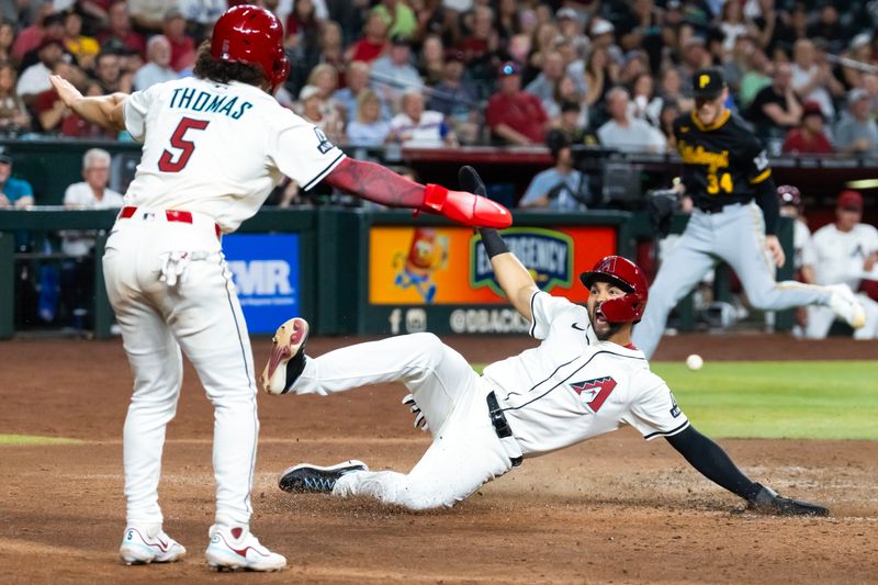 May 27, 2025; Phoenix, Arizona, USA; Arizona Diamondbacks base runner Jordan Lawlar (right) celebrates with Alek Thomas as he slides into home to score against the Pittsburgh Pirates in the fourth inning at Chase Field. Mandatory Credit: Mark J. Rebilas-Imagn Images