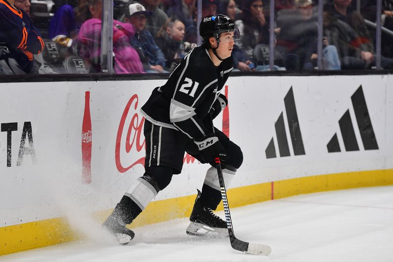 Dec 30, 2023; Los Angeles, California, USA; Los Angeles Kings defenseman Jordan Spence (21) controls the puck against the Edmonton Oilers during the first period at Crypto.com Arena. Mandatory Credit: Gary A. Vasquez-USA TODAY Sports