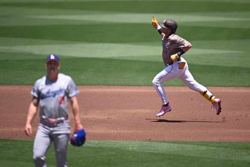 May 12, 2024; San Diego, California, USA; San Diego Padres first baseman Jake Cronenworth (right) rounds the bases after hitting a home run as Los Angeles Dodgers starting pitcher Walker Buehler (21) looks on during the first inning at Petco Park. Mandatory Credit: Orlando Ramirez-USA TODAY Sports