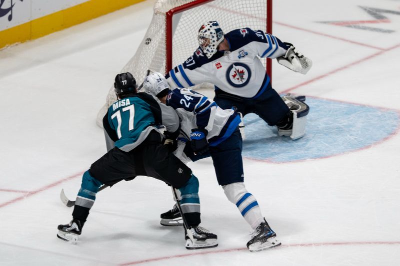 Feb 28, 2026; San Jose, California, USA; San Jose Sharks center Michael Misa (77) scores a goal in overtime against Winnipeg Jets defenseman Haydn Fleury (24) and Winnipeg Jets goaltender Connor Hellebuyck (37) at SAP Center at San Jose. Mandatory Credit: Neville E. Guard-Imagn Images