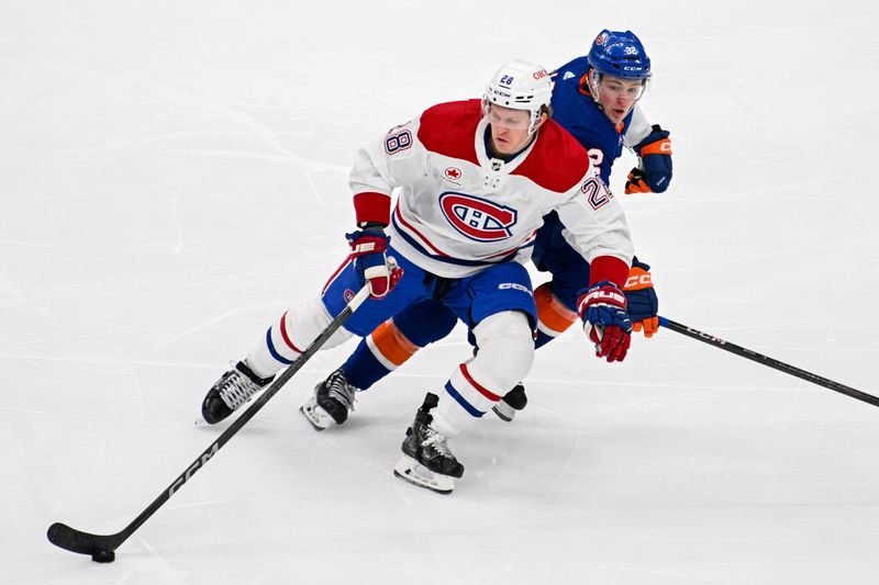 Apr 11, 2024; Elmont, New York, USA; Montreal Canadiens center Christian Dvorak (28) skates with the puck chased by New York Islanders center Kyle MacLean (32) during the second period at UBS Arena. Mandatory Credit: Dennis Schneidler-USA TODAY Sports