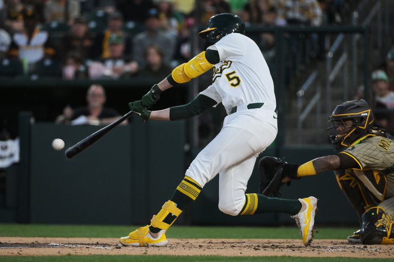 Apr 8, 2025; West Sacramento, California, USA; Athletics shortstop Jacob Wilson (5) hits an RBI single against the San Diego Padres during the first inning at Sutter Health Park. Mandatory Credit: Ed Szczepanski-Imagn Images