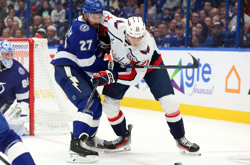 Nov 27, 2024; Tampa, Florida, USA; Tampa Bay Lightning defenseman Ryan McDonagh (27) and Washington Capitals center Aliaksei Protas (21) fight to control the puck during the second period at Amalie Arena. Mandatory Credit: Kim Klement Neitzel-Imagn Images