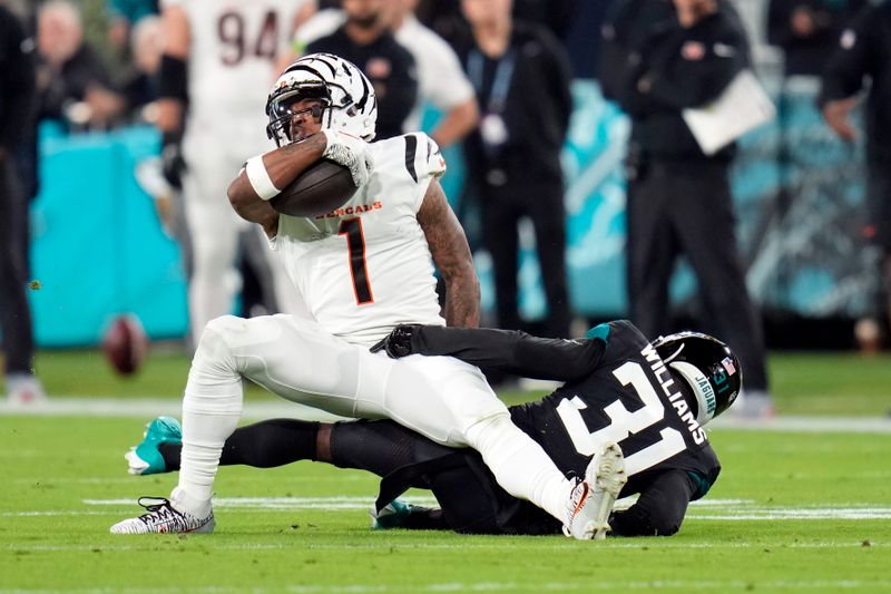 Cincinnati Bengals wide receiver Ja'Marr Chase (1) is stopped by Jacksonville Jaguars cornerback Darious Williams (31) after a reception during the first half of an NFL football game, Monday, Dec. 4, 2023, in Jacksonville, Fla. (AP Photo/John Raoux)