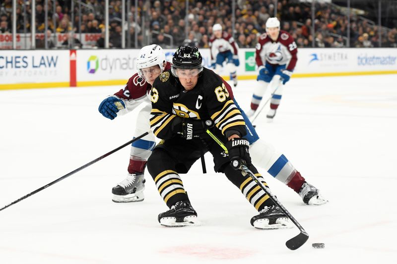 Jan 18, 2024; Boston, Massachusetts, USA; Boston Bruins left wing Brad Marchand (63) controls the puck while Colorado Avalanche defenseman Josh Manson (42) defends during the first period at TD Garden. Mandatory Credit: Bob DeChiara-USA TODAY Sports