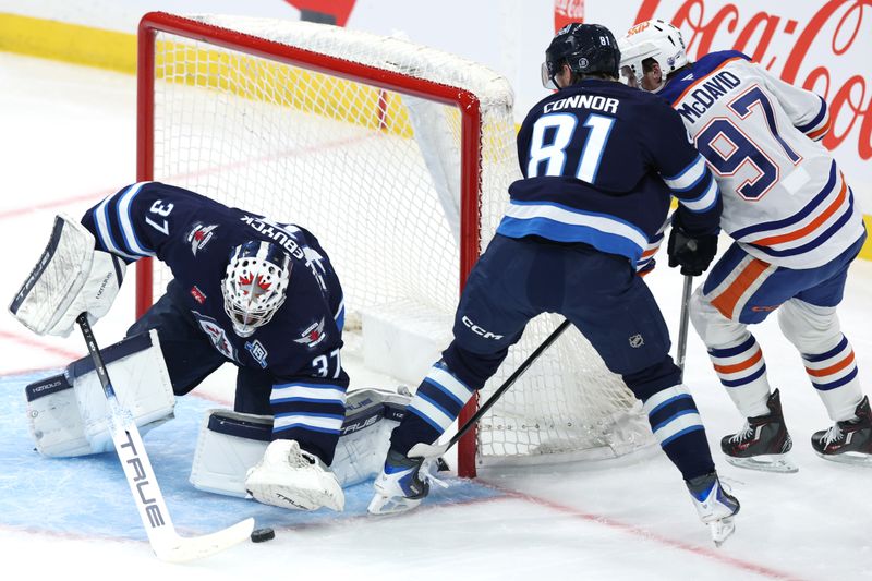 Dec 29, 2025; Winnipeg, Manitoba, CAN; Winnipeg Jets goaltender Connor Hellebuyck (37) covers up a shot by Edmonton Oilers center Connor McDavid (97) checked by Winnipeg Jets left wing Kyle Connor (81) in the first period at Canada Life Centre. Mandatory Credit: James Carey Lauder-Imagn Images