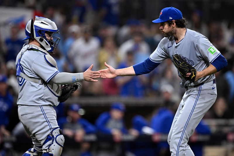 Apr 20, 2024; San Diego, California, USA; Toronto Blue Jays relief pitcher Jordan Romano (right) and catcher Alejandro Kirk (30) celebrate on the field after defeating the San Diego Padres at Petco Park. Mandatory Credit: Orlando Ramirez-USA TODAY Sports