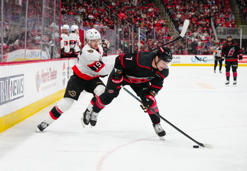 Nov 16, 2024; Raleigh, North Carolina, USA;  Carolina Hurricanes defenseman Dmitry Orlov (7) controls the puck against Ottawa Senators right wing Drake Batherson (19) during the first period at Lenovo Center. Mandatory Credit: James Guillory-Imagn Images