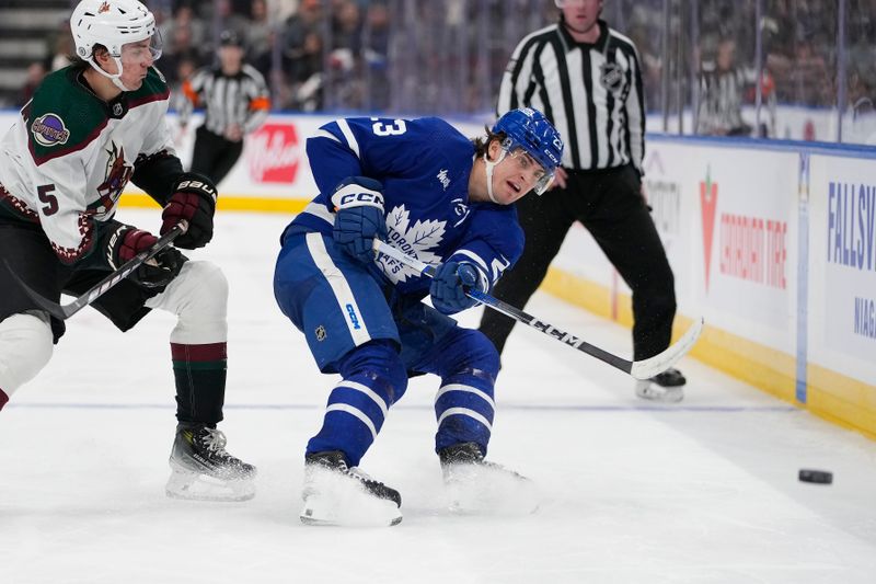 Feb 29, 2024; Toronto, Ontario, CAN; Toronto Maple Leafs forward Matthew Knies (23) shoots the puck into the offensive zone as Arizona Coyotes defenseman Michael Kesselring (5) closes in  during the third period at Scotiabank Arena. Mandatory Credit: John E. Sokolowski-USA TODAY Sports