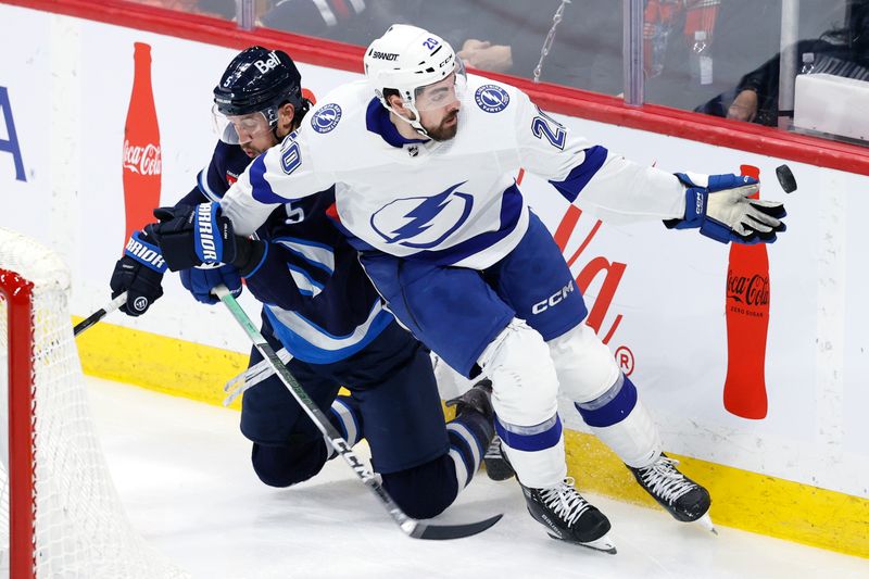 Jan 2, 2024; Winnipeg, Manitoba, CAN; Tampa Bay Lightning left wing Nicholas Paul (20) gloves the puck away from a fallen Winnipeg Jets defenseman Brenden Dillon (5) in the third period at Canada Life Centre. Mandatory Credit: James Carey Lauder-USA TODAY Sports