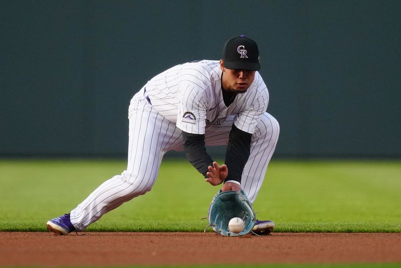 Apr 21, 2024; Denver, Colorado, USA; Colorado Rockies shortstop Ezequiel Tovar (14) fields the ball in the first inning against the Seattle Mariners at Coors Field. Mandatory Credit: Ron Chenoy-USA TODAY Sports