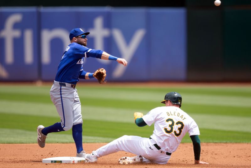 Jun 20, 2024; Oakland, California, USA; Kansas City Royals second baseman Garrett Hampson (2) throws over Oakland Athletics center fielder JJ Bleday (33) to complete a double play during the first inning at Oakland-Alameda County Coliseum. Mandatory Credit: D. Ross Cameron-USA TODAY Sports