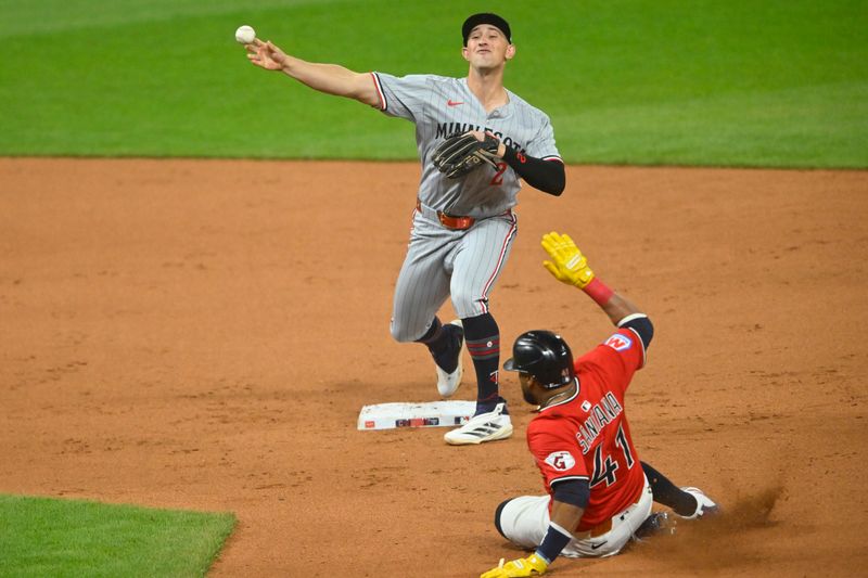 Apr 29, 2025; Cleveland, Ohio, USA; Minnesota Twins second baseman Brooks Lee (2) turns a double play beside Cleveland Guardians first baseman Carlos Santana (41) in the fourth inning at Progressive Field. Mandatory Credit: David Richard-Imagn Images