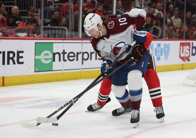 Apr 2, 2025; Chicago, Illinois, USA; Colorado Avalanche center Charlie Coyle (10) and Chicago Blackhawks defenseman Sam Rinzel (6) battle for control of the puck during the second period at United Center. Mandatory Credit: Talia Sprague-Imagn Images
