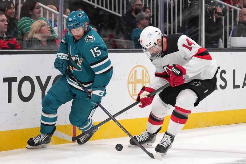 Jan 4, 2025; San Jose, California, USA; San Jose Sharks right wing Nikolai Kovalenko (15) and New Jersey Devils right wing Nathan Bastian (14) reach for the puck during the first period at SAP Center at San Jose. Mandatory Credit: Darren Yamashita-Imagn Images