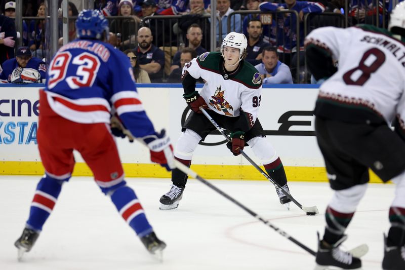 Oct 16, 2023; New York, New York, USA; Arizona Coyotes center Logan Cooley (92) controls the puck against New York Rangers center Mika Zibanejad (93) during the first period at Madison Square Garden. Mandatory Credit: Brad Penner-USA TODAY Sports