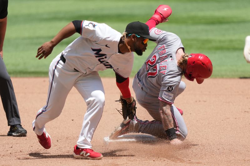Apr 23, 2025; Miami, Florida, USA;  Cincinnati Reds right fielder Jake Fraley (27) steals second base in the fifth inning as Miami Marlins second baseman Otto Lopez (6) applies the late tag at loanDepot Park. Mandatory Credit: Jim Rassol-Imagn Images