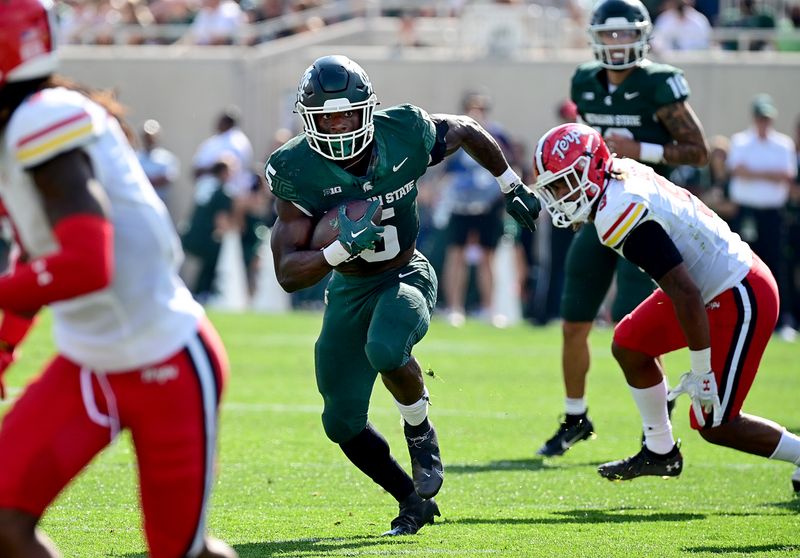 Sep 23, 2023; East Lansing, Michigan, USA;  Michigan State Spartans running back Nathan Carter (5) runs past Maryland Terrapins linebacker Fa'Najae Gotay (9) in the first quarter at Spartan Stadium. Mandatory Credit: Dale Young-USA TODAY Sports