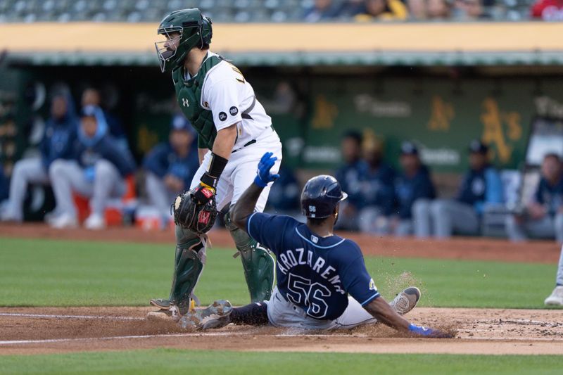 Jun 14, 2023; Oakland, California, USA;  Tampa Bay Rays left fielder Randy Arozarena (56) slides home safe during the second inning against Oakland Athletics catcher Shea Langeliers (23) at Oakland-Alameda County Coliseum. Mandatory Credit: Stan Szeto-USA TODAY Sports