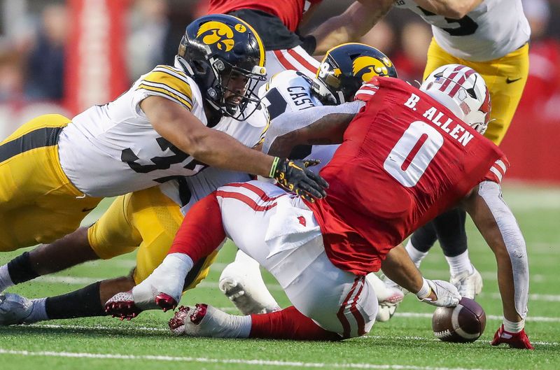 Oct 14, 2023; Madison, Wisconsin, USA; Iowa Hawkeyes linebacker Kyler Fisher (37) and defensive back Sebastian Castro (29) force a fumble by Wisconsin Badgers running back Braelon Allen (0) at Camp Randall Stadium. Mandatory Credit: Tork Mason-USA TODAY Sports