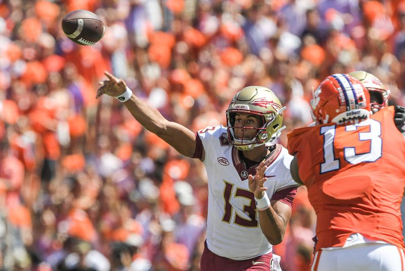 Sep 23, 2023; Clemson, South Carolina, USA; Florida State Seminoles quarterback Jordan Travis (13) throws a pass against Clemson Tigers defensive tackle Tyler Davis (13) during the second quarter at Memorial Stadium. Mandatory Credit: Ken Ruinard-USA TODAY Sports