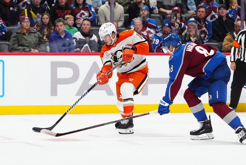 Oct 18, 2024; Denver, Colorado, USA; Anaheim Ducks right wing Troy Terry (19) shoots the puck as Colorado Avalanche defenseman Cale Makar (8) defends in third period at Ball Arena. Mandatory Credit: Ron Chenoy-Imagn Images