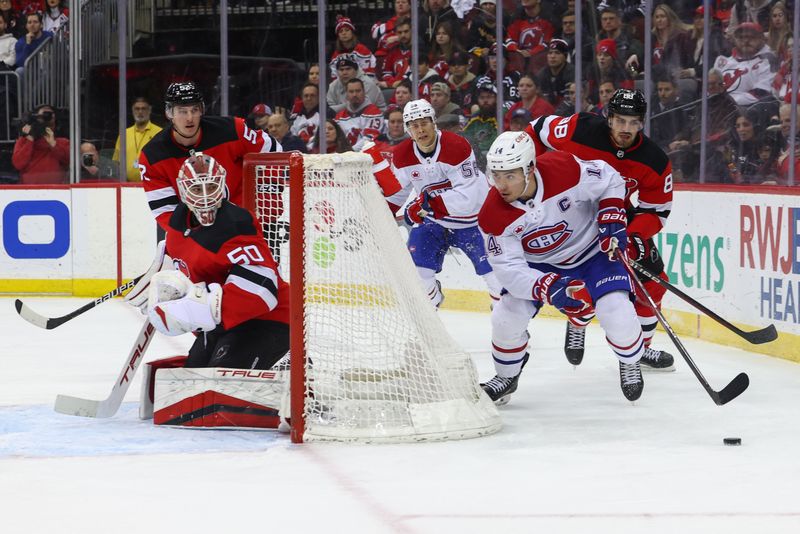 Jan 17, 2024; Newark, New Jersey, USA; Montreal Canadiens center Nick Suzuki (14) skates with the puck while New Jersey Devils goaltender Nico Daws (50) defends his net during the third period at Prudential Center. Mandatory Credit: Ed Mulholland-USA TODAY Sports