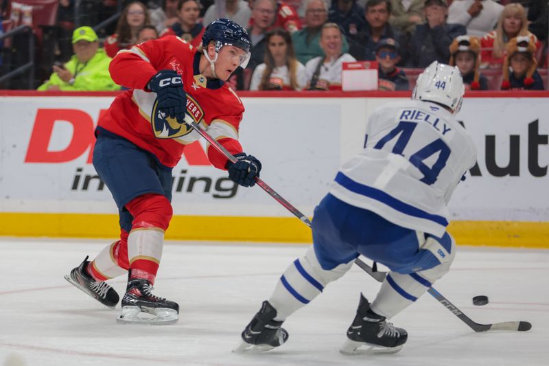 Apr 8, 2025; Sunrise, Florida, USA; Florida Panthers center Anton Lundell (15) shoots the puck as Toronto Maple Leafs defenseman Morgan Rielly (44) defends during the second period at Amerant Bank Arena. Mandatory Credit: Sam Navarro-Imagn Images