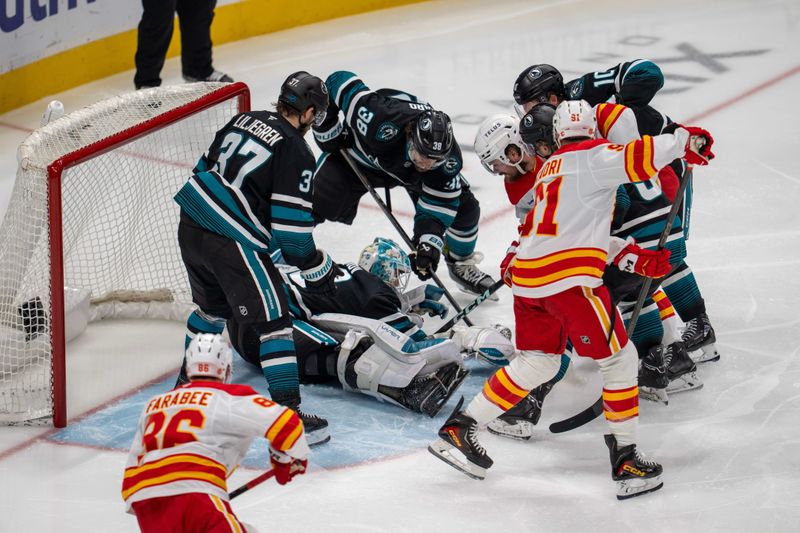 Dec 16, 2025; San Jose, California, USA; San Jose Sharks goaltender Yaroslav Askarov (30) makes a save against Calgary Flames defenseman Rasmus Andersson (4) during the third period at SAP Center at San Jose. Mandatory Credit: Neville E. Guard-Imagn Images